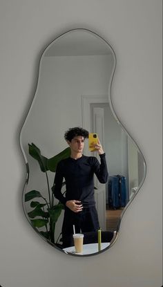 a man taking a selfie in front of a mirror with a drink and cell phone