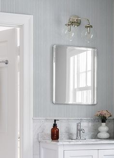 a bathroom sink with a mirror above it and a vase on the counter next to it