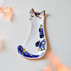 a white and blue cat brooch sitting on top of a table