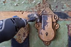 an electric drill is being used to paint a wall with peeling paint and rust on it