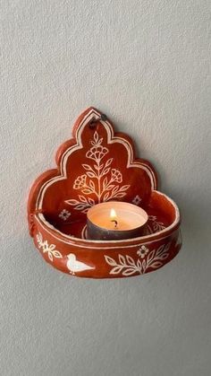 a candle is lit in a bowl shaped like a flower and leaves on the wall