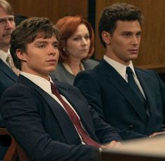 three people sitting next to each other in suits