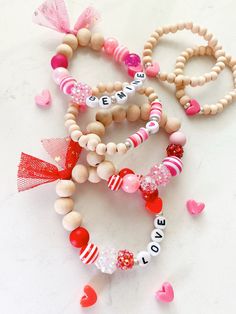 several bracelets with words and hearts are on a white table next to some candy