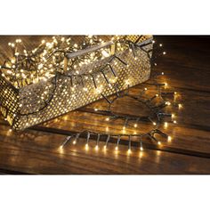 a basket with christmas lights on it sitting on top of a wooden table next to a string of lights