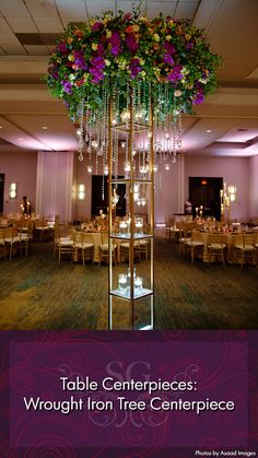 a tall tower with flowers and candles on it's sides in the middle of a banquet hall