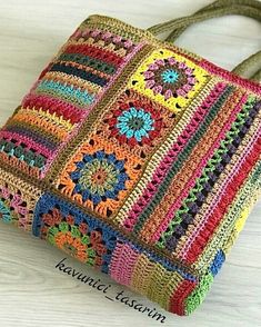 a multicolored crocheted bag sitting on top of a white wooden table