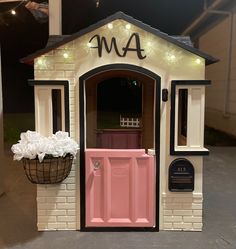 a toy house with flowers and lights on the front door is decorated in pink, white and black