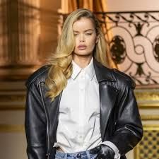 a model walks down the runway in a white shirt and black leather jacket with blue jeans