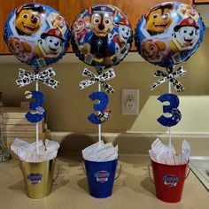 three birthday balloons in the shape of numbers with paw patrol characters and cupcakes