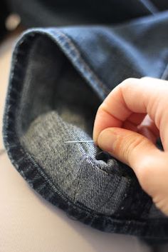 someone is sewing on the inside of a pair of blue jeans with a needle in their pocket