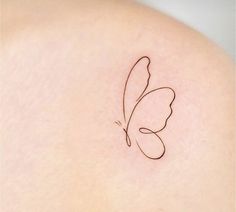 a small butterfly tattoo on the back of a woman's shoulder