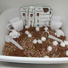 a white bowl filled with chocolate and marshmallows on top of coffee beans