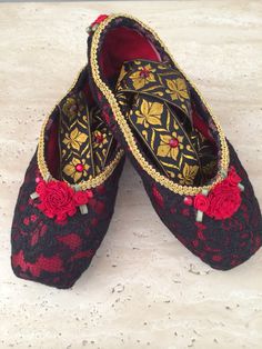 two pairs of black and red shoes with flowers on the soles are sitting on a white surface