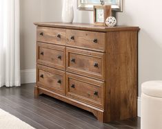 a wooden dresser sitting in front of a mirror on top of a hard wood floor