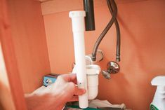 a person is holding a water faucet in front of a sink with soap dispenser