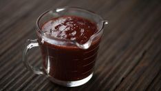 a glass pitcher filled with red liquid on top of a wooden table