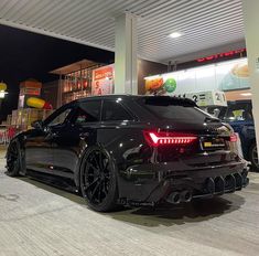 a black sports car parked in front of a gas station