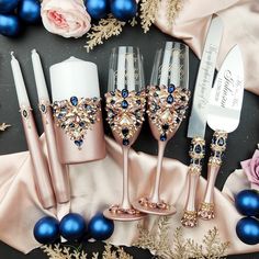 there are some wine glasses and silverware next to blue christmas balls on the table