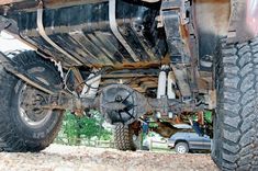 the rear end of a large truck parked on top of a dirt field