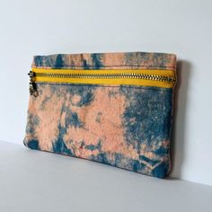 a blue and yellow tie - dyed pouch with zippers on the front, sitting on a white surface