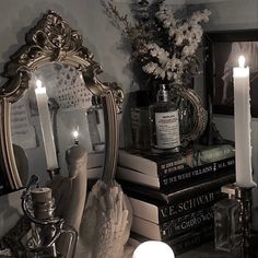 a mirror sitting on top of a table next to a pile of books and candles