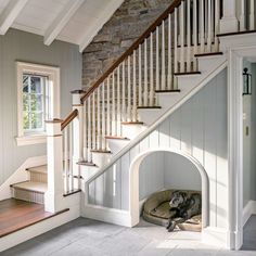 a dog is laying in his bed under the stairs at the bottom of the stairs