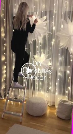 a woman standing on a ladder in front of a christmas decoration