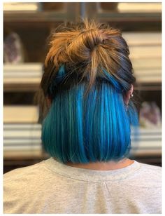 a woman with blue and brown hair has her back to the camera