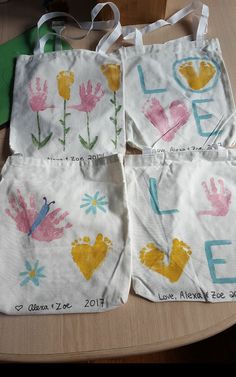 three bags with handprints on them sitting on a table next to some scissors