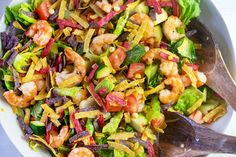 a salad with shrimp, lettuce, and other vegetables in a white bowl