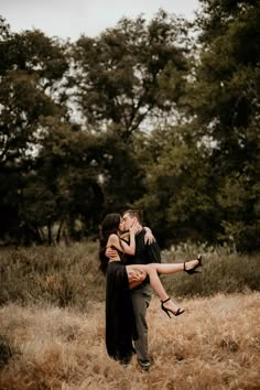 a man and woman hugging in the middle of a field