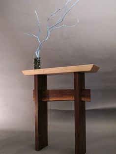 a wooden table topped with a vase filled with water and a tree branch on top of it