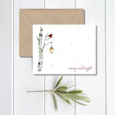 a card with a bird sitting on a tree branch next to an envelope that says merry and bright