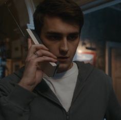 a man talking on a cell phone while wearing a sweatshirt and looking at the camera