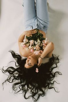 a woman laying on the ground with flowers in her hair and jeans over her body