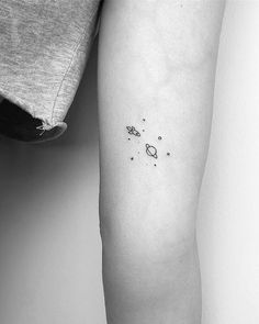 a person with a small tattoo on their arm that has planets and stars all over it