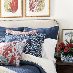 a bed with blue and red pillows on top of it next to two framed pictures