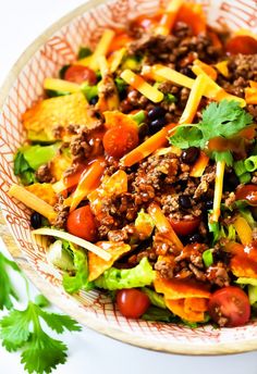 a salad in a bowl with cheese, tomatoes, lettuce and other toppings