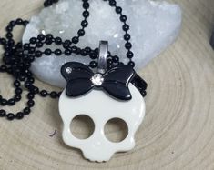 Skull Head Pendant Necklace on a Black Ball Chain:Made of hard plastic and metal pieces these skull pendant necklaces are awsome for the lil gothic girl in you....or in someone that you know.White with a Black Bow. #skullhead #skullnecklace #skullheadnecklace #skullpendant #girlsnecklace Emo Black Skull Jewelry, Gothic Skull Print Necklace For Gifts, Edgy Skull-shaped Chain Jewelry, Black Edgy Skull Necklace, Silver Gothic Skull Necklace, Red Earrings Stud, Painting The Roses Red, Skull Pendant Necklace, Hamsa Jewelry