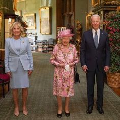 three people in suits and hats are walking down the hallway with one woman wearing a pink hat