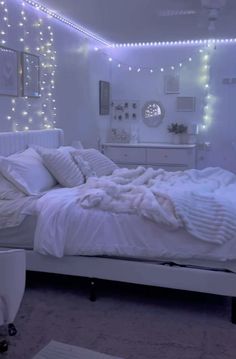 a bed with white sheets and pillows in a room that has lights on the walls