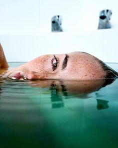 a woman is floating in the water with her eyes closed