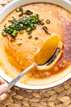 a person holding a spoon in a bowl of soup