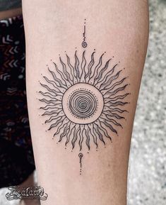 a woman's leg with a black and white sun tattoo on the side of her thigh