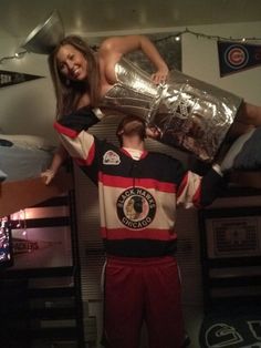 two people standing on top of each other in a room with bunk beds and lights