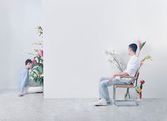 two men sitting on chairs with flowers in front of them