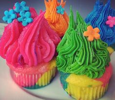 three cupcakes with different colored frosting on top of each other, one is decorated like a tree and the other has flowers