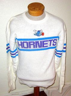 a white sweater with the word hornet's on it sitting on top of a wooden stand