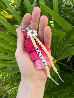 a hand holding a key chain with beads and tassels