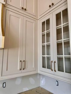 the kitchen cabinets are all white and have glass doors on each side, along with brass pulls